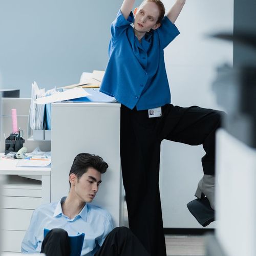 Man sitting at an office desk taking a moment to stretch his back.